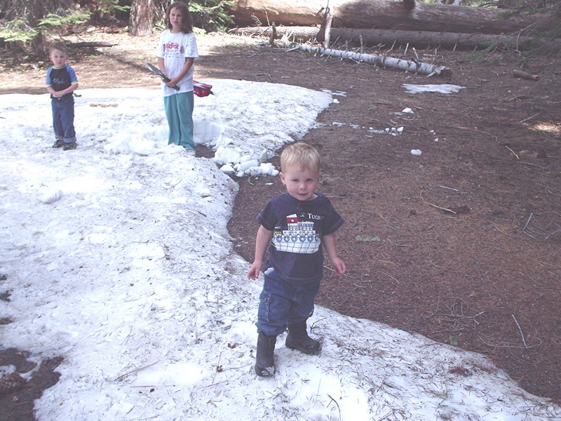 Man posing with a large snowman at camp in the snow, 2025